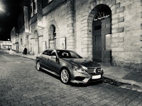 a mercedes e class parked on a cobblestone street